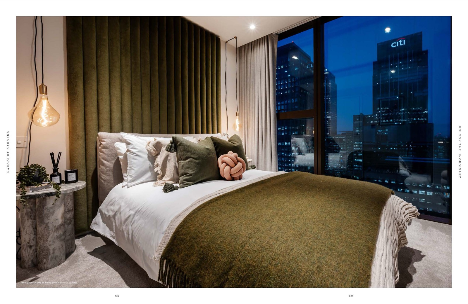 Harcourt Gardens South Quay Plaza Canary Wharf E14 principal bedroom with olive velvet headboard, floor-to-ceiling glazing and night view of the illuminated Citi tower